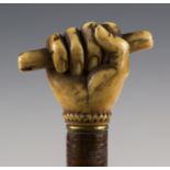 A 19th century sectional joined leather walking cane, the ivory handle carved as a hand holding a