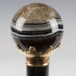 A late 19th century ebonized walking cane, the spherical banded agate handle with gilt metal collar,