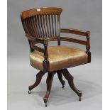 An Edwardian walnut framed comb back revolving desk chair with a brown leather seat, height 90cm,