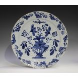 An English Delft charger, 18th century, painted in blue with a vase and flowers, the rim similarly