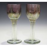 A pair of George Elliott of Bewdley art glass goblets, the iridescent bowls with mottled pink and