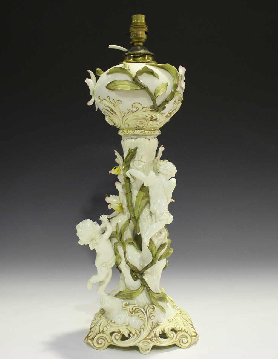 A Moore Brothers oil lamp, late 19th century, the trunk stem applied with four putti and entwined