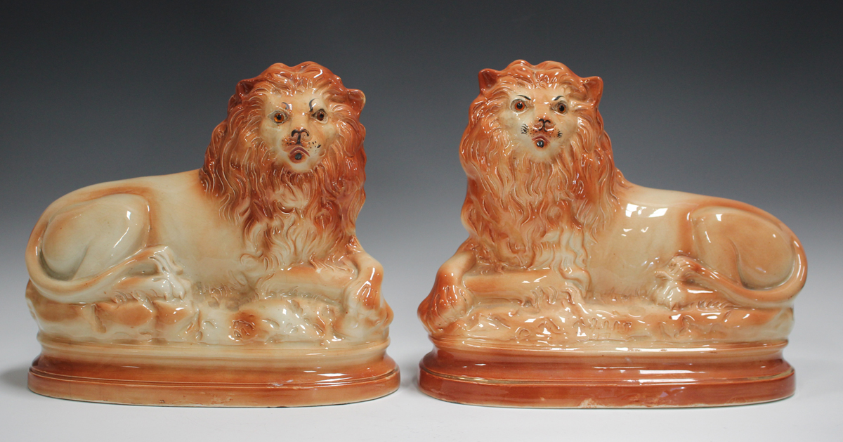 A pair of Staffordshire pottery lions, late 19th/early 20th century, inset with glass eyes, length