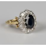 An 18ct gold, sapphire and diamond oval cluster ring, claw set with the oval cut sapphire within a