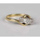 An 18ct gold and diamond three stone ring, mounted with circular cut diamonds in a crossover design,