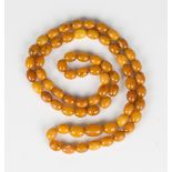 A single row necklace of sixty-eight slightly graduated oval varicoloured mottled butterscotch