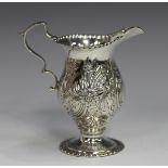 An Edwardian silver cream jug of ogee baluster form, embossed in 18th century style with flowers and