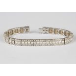 An 18ct white gold and diamond bracelet, designed as a row of circular cut diamonds between two rows