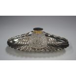 A late Victorian silver inkstand of scalloped form, fitted with a cut glass well with silver