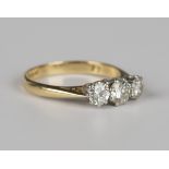 A gold, platinum and diamond three stone ring, claw set with a row of circular cut diamonds, the