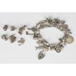 A silver charm bracelet, fitted with a variety of mostly silver charms, including a biplane, a