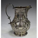A Victorian silver milk jug of baluster form with scalloped spout and scroll handle, the body