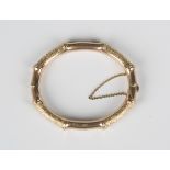 A 9ct gold oval hinged bangle of bamboo effect design with engraved decoration, on a snap clasp,