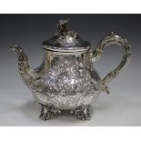 A Victorian silver teapot, the low-bellied body embossed with scrolls and flowers, beneath a