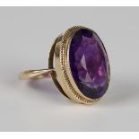 A 9ct gold ring, collet set with an oval cut amethyst within a ropetwist wirework surround, London