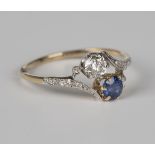 A gold, sapphire and diamond ring in a crossover design, claw set with the principal circular cut