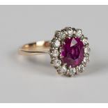 A gold, magenta sapphire and diamond oval cluster ring, claw set with the oval cut magenta