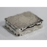 A late Victorian silver vinaigrette of shaped rectangular outline, engraved with foliate scrolls,