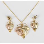 A three colour gold pendant, designed as two vine leaves and a bunch of grapes, detailed '10K',