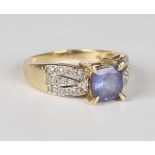 An 18ct gold, tanzanite and diamond ring, claw set with the cushion cut tanzanite between diamond