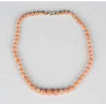 A single row necklace of graduated coral beads, each bead carved in a floral design, on a boltring