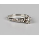 A diamond single stone ring, claw set with a cushion cut diamond between diamond three stone