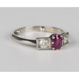 A platinum ring, claw set with a cushion cut ruby between two cushion cut diamonds in square