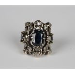 A sapphire and diamond ring in a pierced curved rectangular panel shaped design, mounted with the