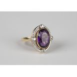 An 18ct two colour gold ring, collet set with an oval cut amethyst, the openwork surround set with