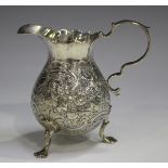 A George II silver cream jug, the baluster body chased with fruit and scrolls, on trefid feet,