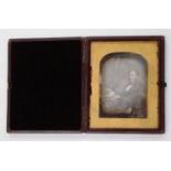 PHOTOGRAPHS. A leather-cased daguerreotype by Kilburn of a gentleman seated by a desk, image size