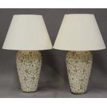 A pair of modern pottery table lamps, painted with flowering stems on a cream ground, fitted with