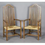 A pair of Edwardian Arts and Crafts oak framed comb back elbow chairs, attributed to Liberty & Co,