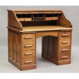 An early 20th century oak roll-top desk, the tambour shutter enclosing a fitted interior above an