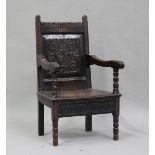 A 17th century oak Wainscot armchair, the carved panel back above a solid seat, on bobbin turned