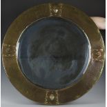 An Arts and Crafts brass framed circular wall mirror, in the manner of Liberty & Co, the bevelled