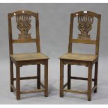 A pair of late 19th century French oak hall chairs with carved and pierced splat backs, the solid