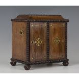 A Regency rosewood and brass inlaid table-top cabinet, the door hinged to reveal four drawers, one