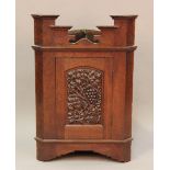An Edwardian Arts and Crafts stained oak hanging corner cabinet, the shaped pediment above an arched