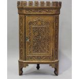 A small late Victorian Arts and Crafts Medieval Revival oak hanging corner cabinet, the