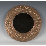 An early 20th Century Arts and Crafts copper circular wall mirror, the frame worked with a band of