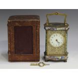 An early 20th century French brass and champlevé enamel serpentine cased carriage timepiece with