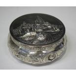 An early 20th century Dutch silver circular box with hinged lid, embossed with buildings and figures