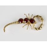 A gold and garnet brooch, designed as a scorpion, mounted with three circular cut garnets,