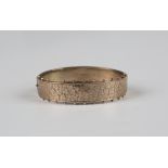 A late Victorian 9ct gold oval hinged bangle, the front with foliate engraved decoration between