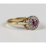 An 18ct gold, ruby and diamond cluster ring, claw set with a cushion cut ruby within a surround of