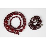 A single row necklace of graduated oval cherry coloured reconstituted amber beads, gross weight 78.