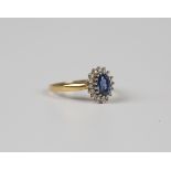 An 18ct gold, sapphire and diamond oval cluster ring, claw set with the oval cut sapphire within a