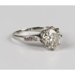 A diamond ring, claw set with the principal circular cut diamond between diamond three stone