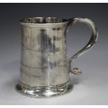 A George II silver mug of tapering cylindrical form with scroll handle above a flared base,